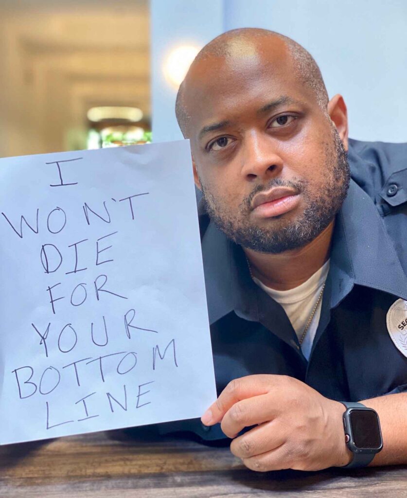 Man holding sign that says "I won't die for your bottom line"